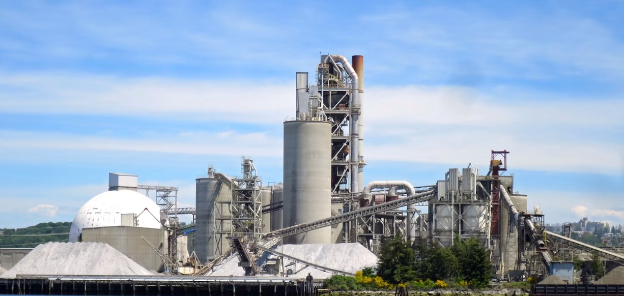 Planta cementera — silos, torre de precalentamiento y transportador de clinker